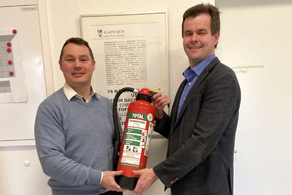 Two people holding a Total fire extinguisher