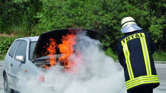 Firefighter dousing a car set ablaze