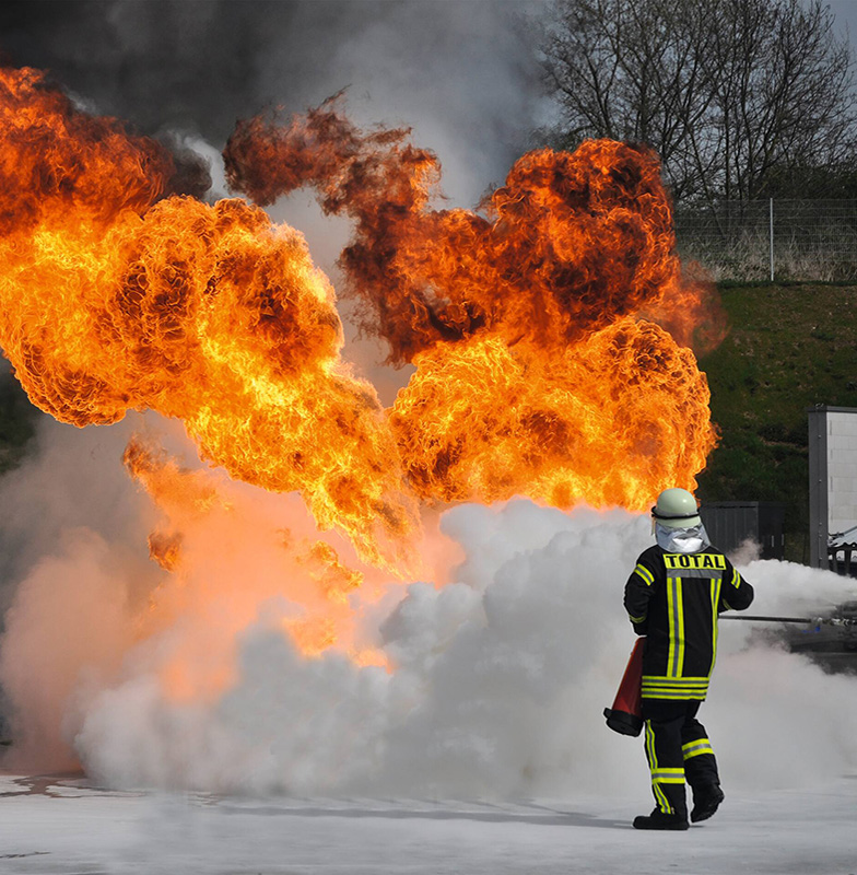 Firefighter in suit dousing a flame in an outdoor space