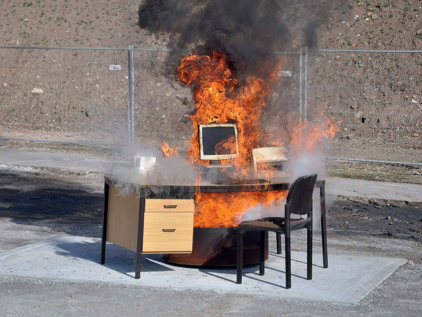 Desktop and chairs set ablaze in an open space