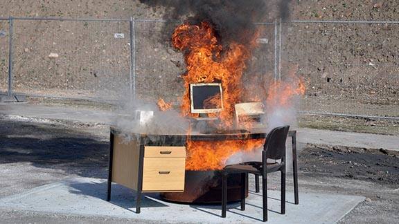 Desktop and chairs set ablaze in an open space
