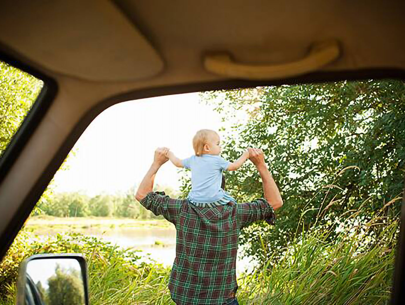 Rear-view image of a father carrying his child on his shoulders
