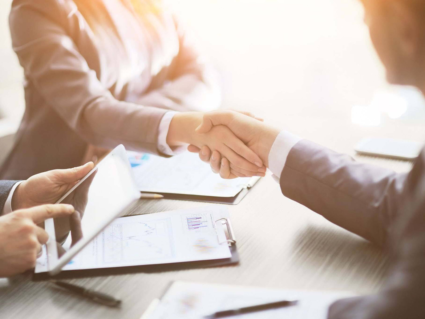 Two people shaking hands sitting across from a table