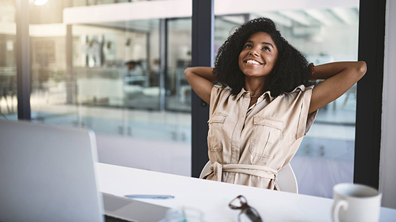 Woman sitting in an office chair in a relaxed position with her hands behind her head