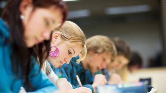 Group of students writing down notes in a classroom