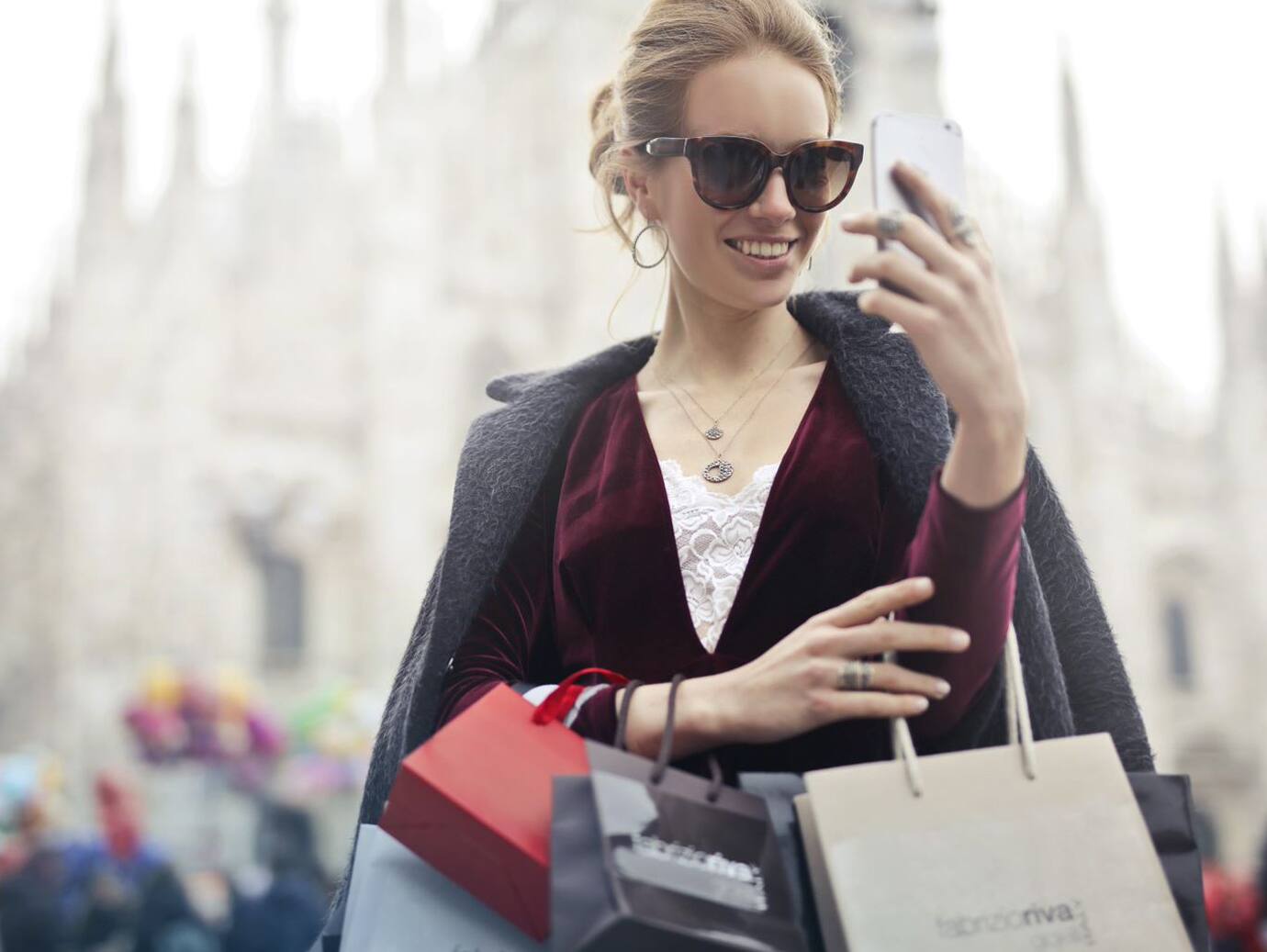 Woman in sunglasses checking the stack of shopping bags in her hand