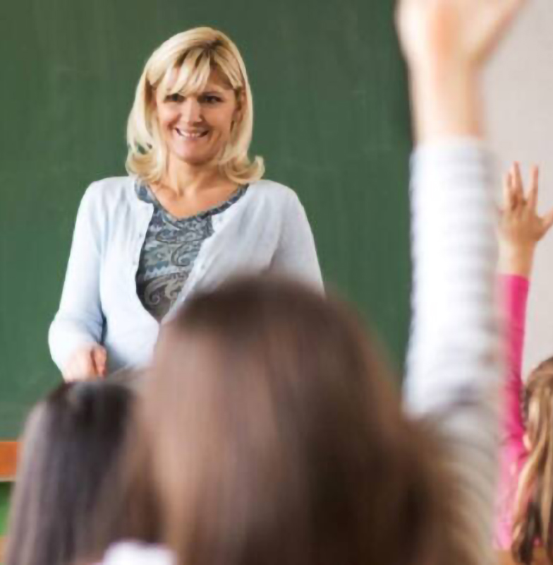 Rear view shot of a group of students raising their hands to answer a question in a classroom
