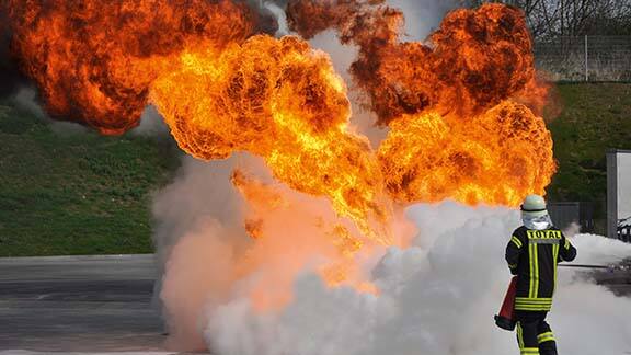 Firefighter in uniform dousing a flame