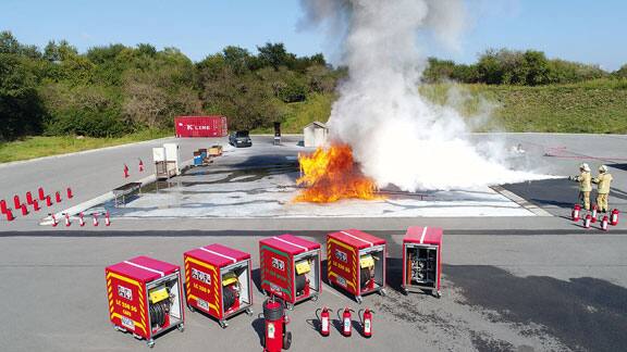 Group of firefighters in uniform dousing a flame in an open space