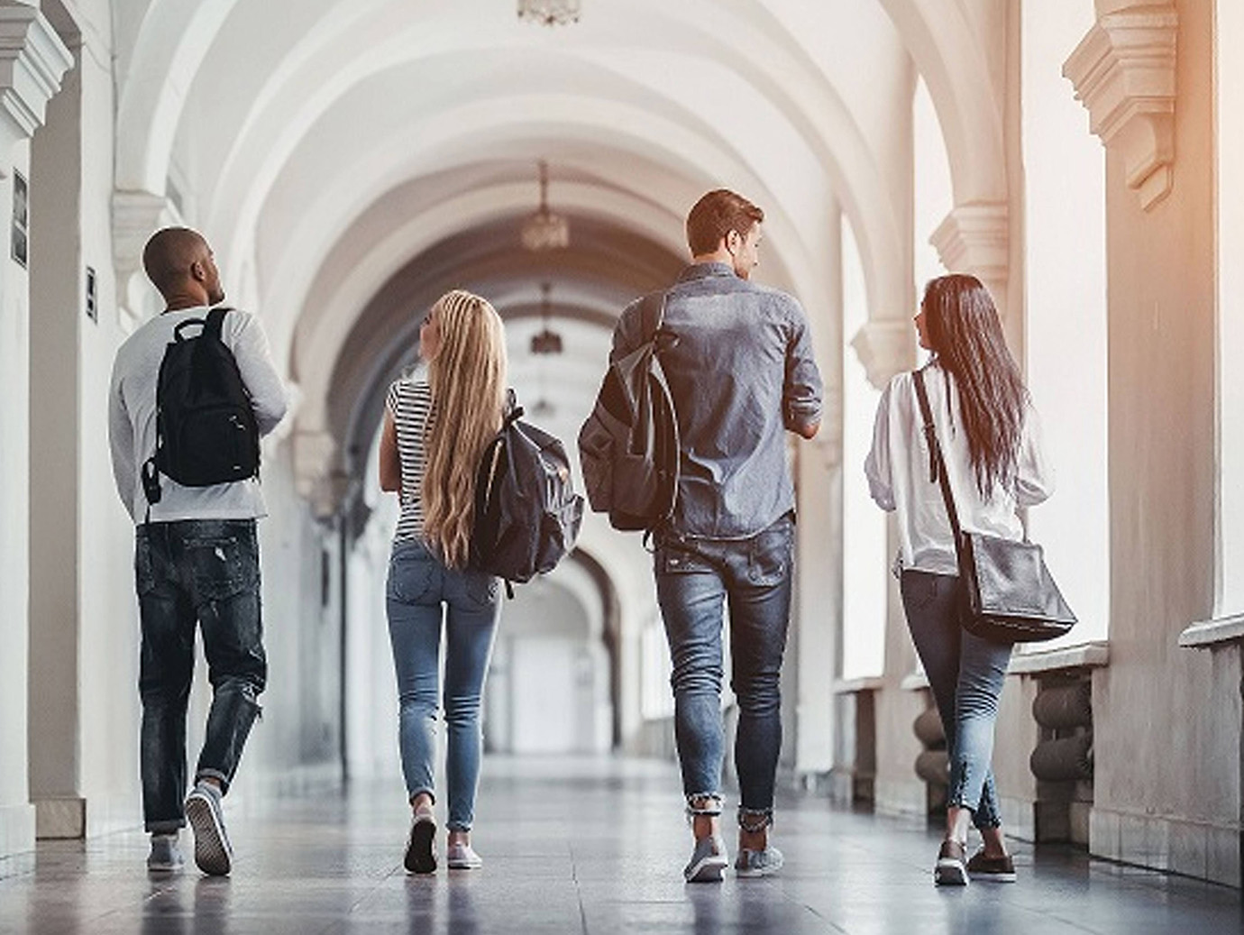 Back view of four university students walking on campus