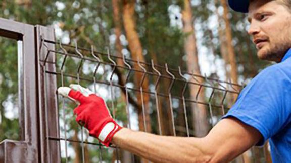 A person fixing the grills laid for the perimeter of the house