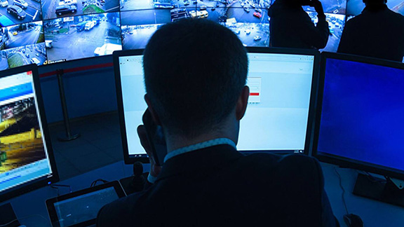 A security person watching the cctv footages while talking over mobile