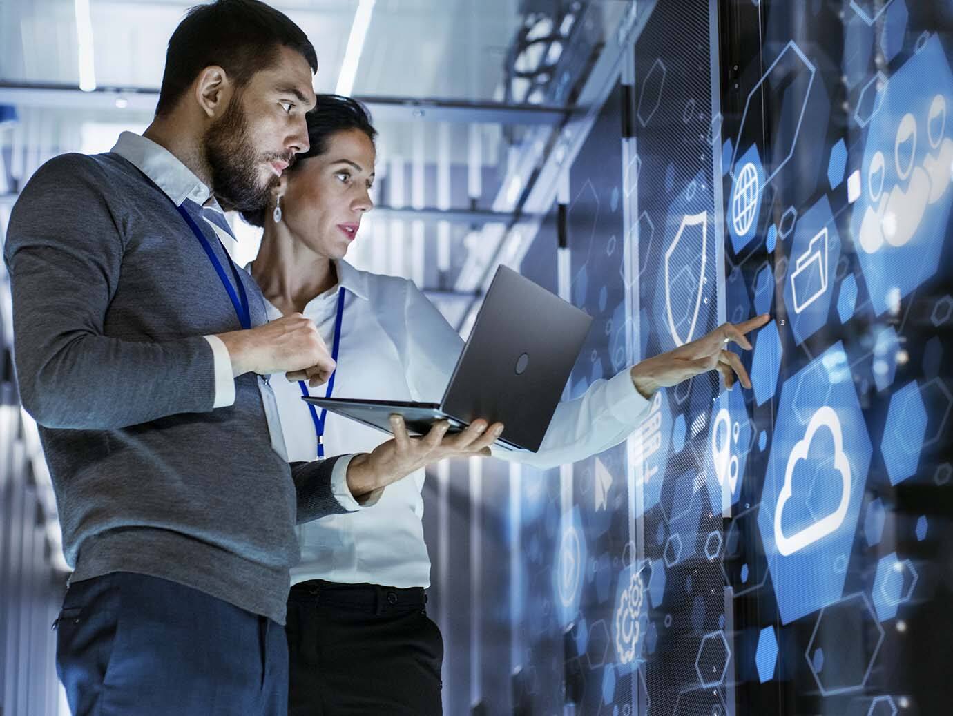 A man and a woman having a conversation while inspecting server racks in a data center
