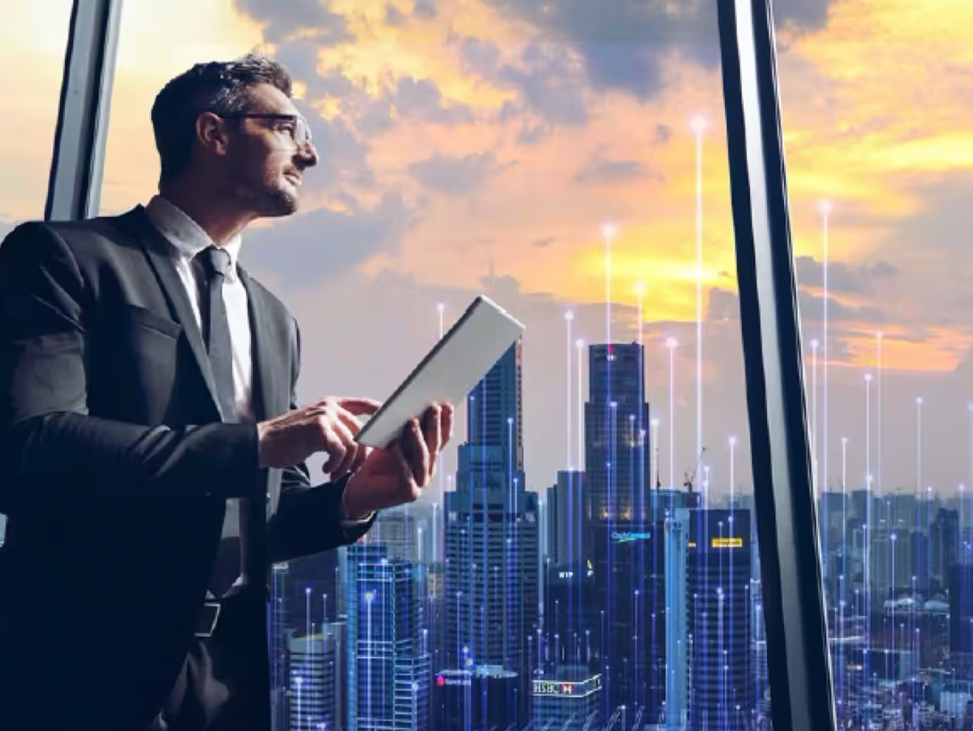 A man looking out of a skyscraper window holding a tab in his hand overlaid with graphics of transmission nodes