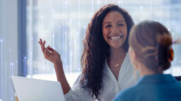 Two female employees having a friendly conversation in office