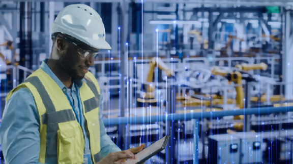 Man in a safety helmet and reflective vest working on a tab overlaid with graphic depicting transmission nodes