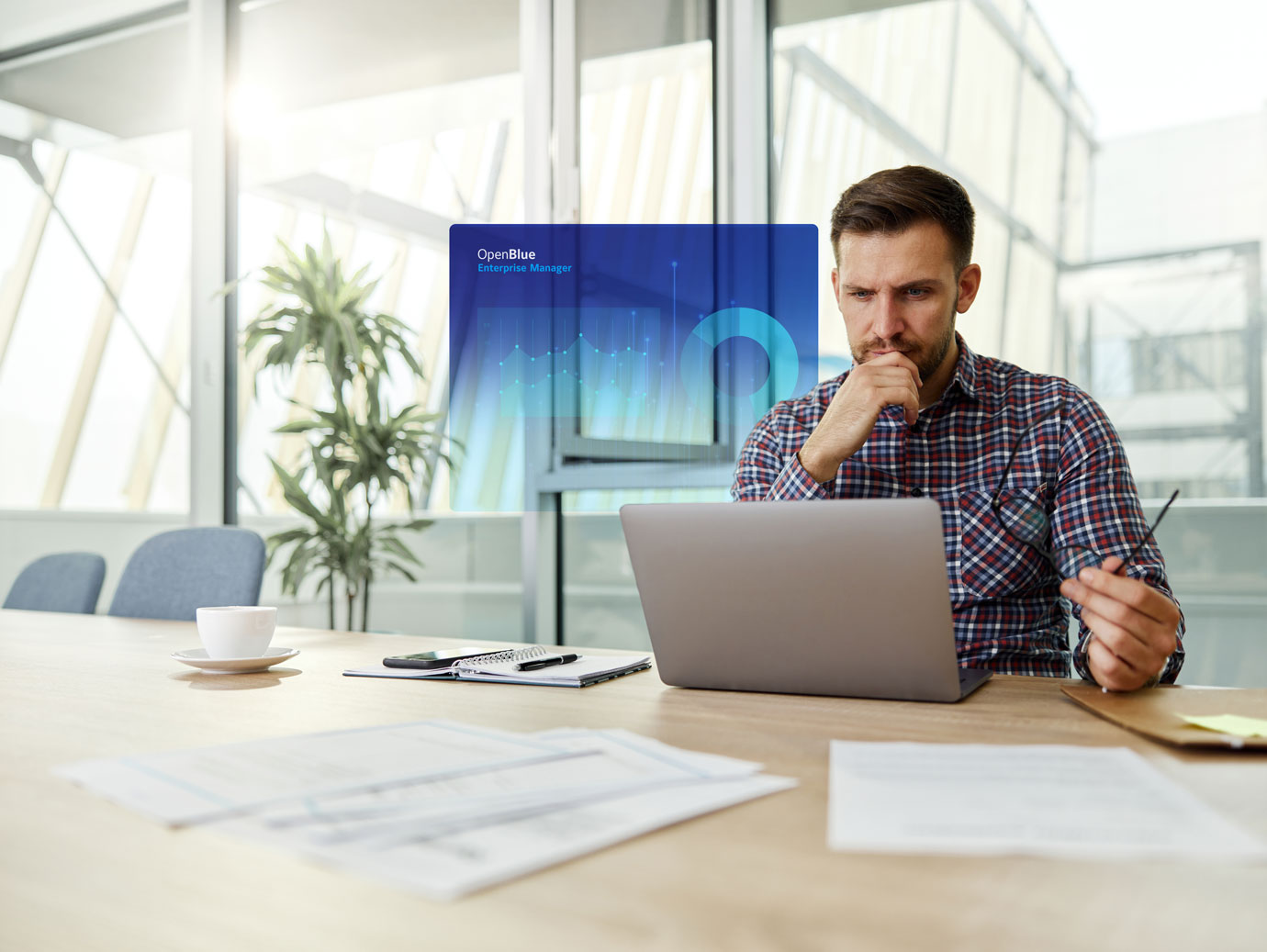 Man using a laptop in office, overlaid with an infographic of OpenBlue Enterprise Manager